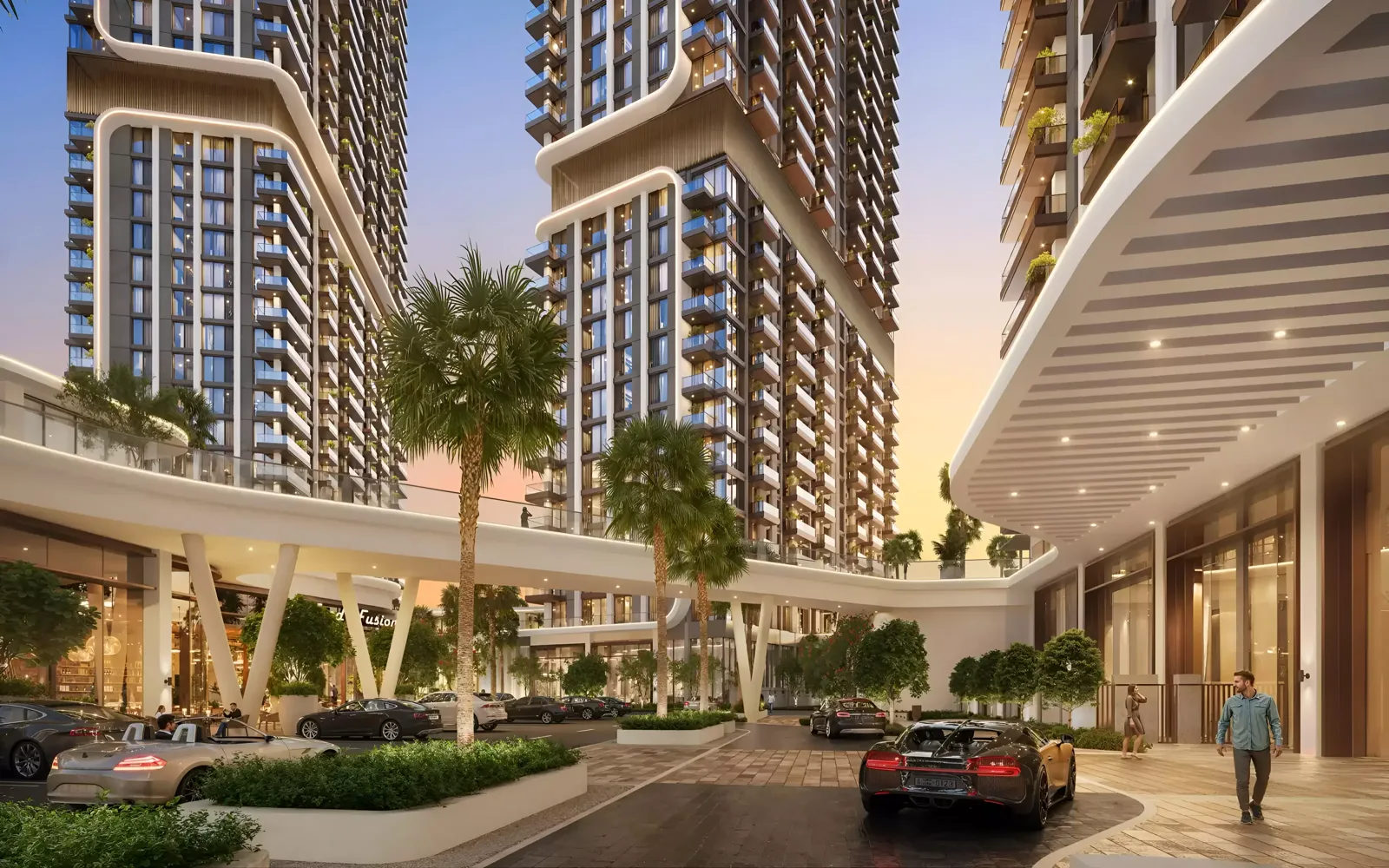 Mirdad Motor City — dusk podium drive with UP towers and retail colonnade