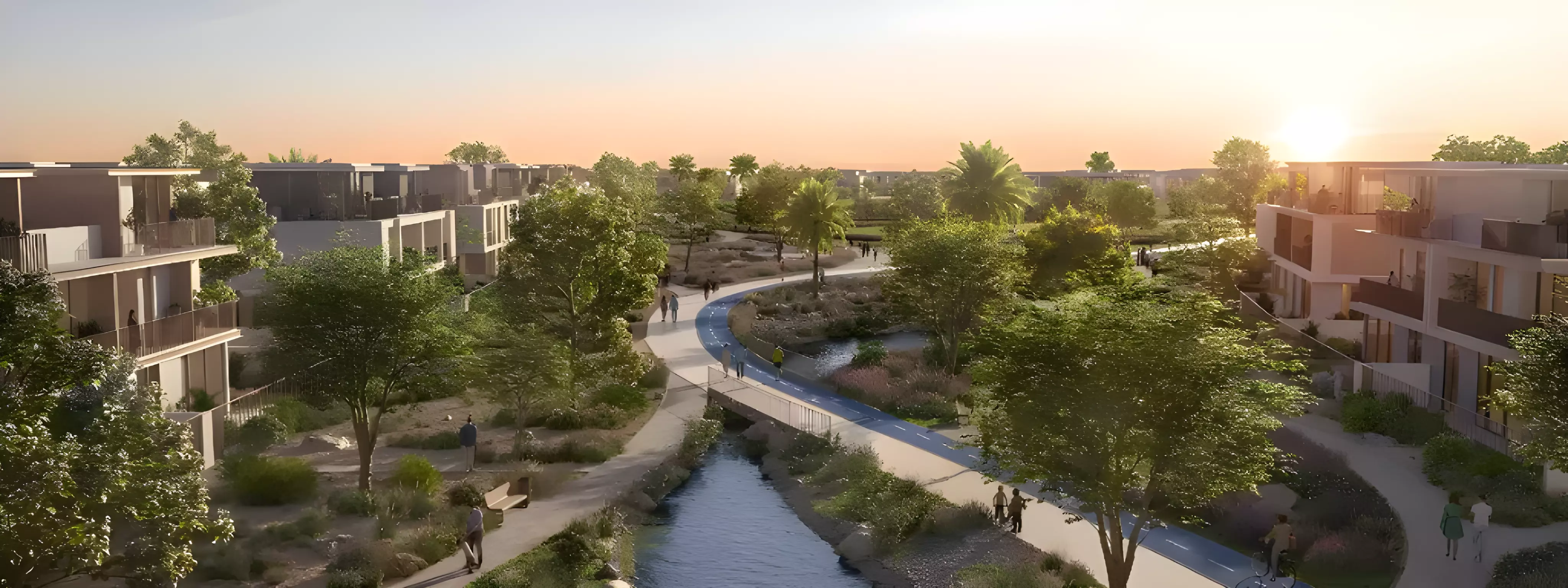The Valley West — aerial marketing still of low-rise townhouse clusters along a landscaped waterway and cycle path at sunset